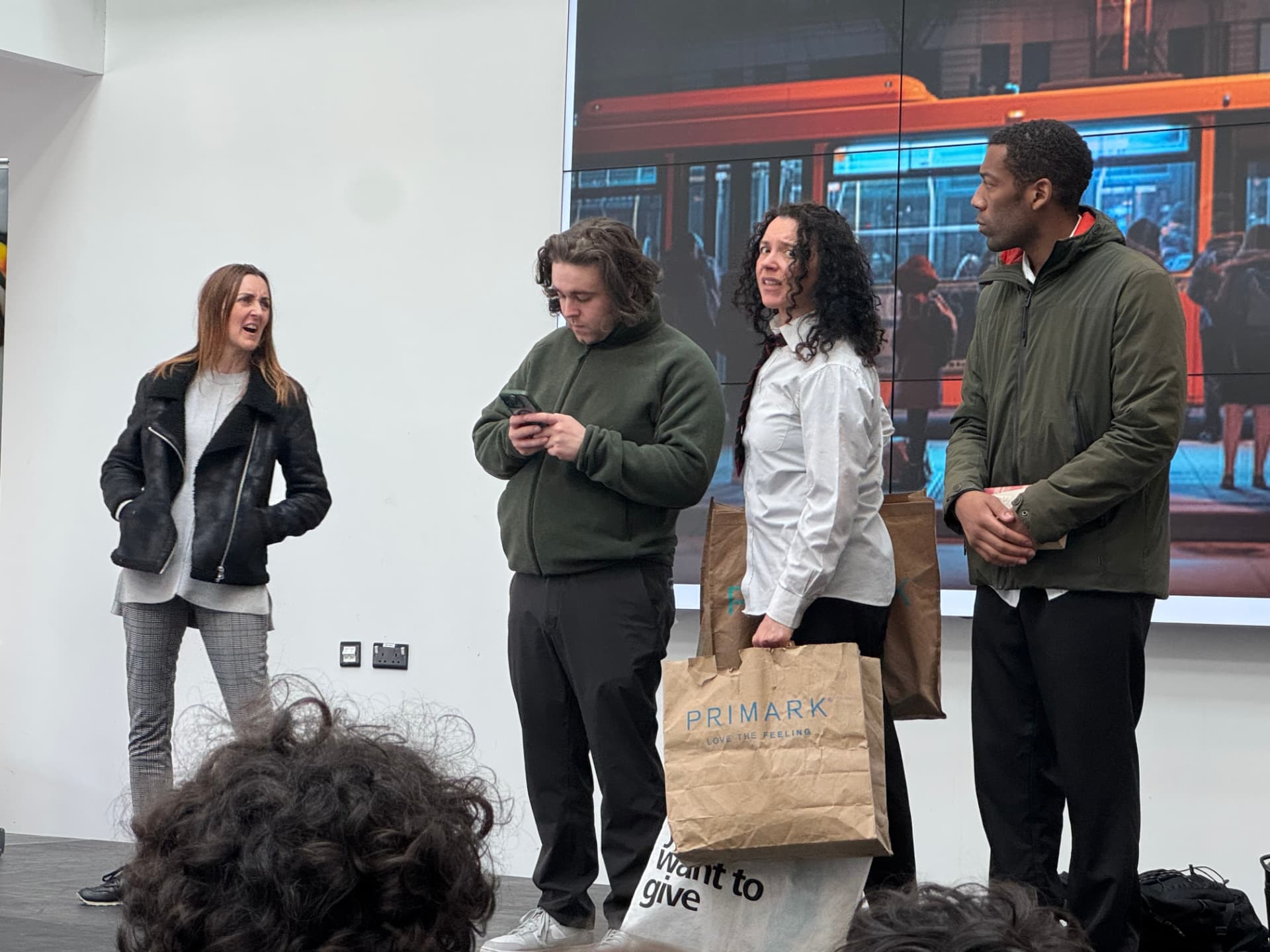 Four Time's Up! actors performing a bus-stop scene in front of a school audience